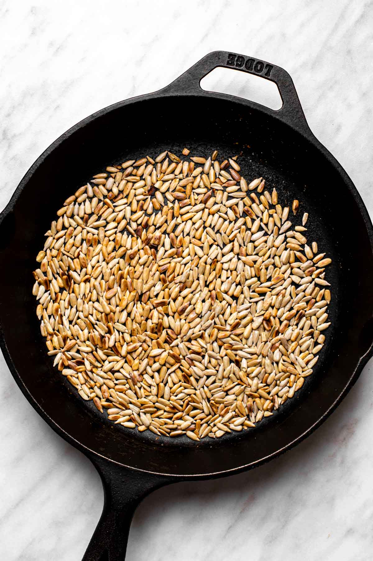 Toasting sunflower seeds in a cast-iron skillet.