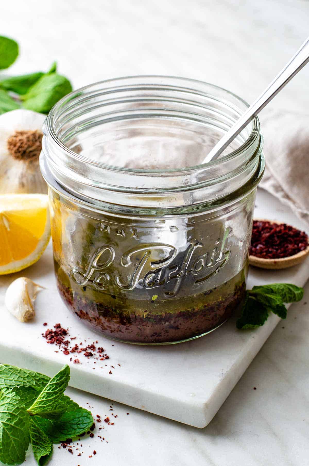 Sumac dressing served in a jar with a spoon in it.