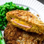 A close-up photo of vegan cordon bleu sliced in half with melted cheese and ham slices inside.
