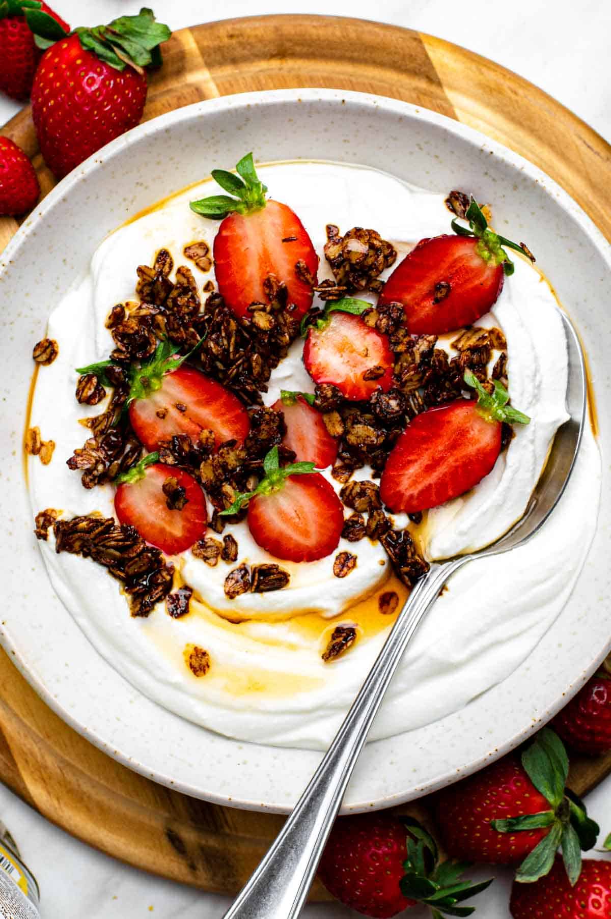 Whipped cottage cheese served in a bowl and topped with maple syrup, granola and fresh berries.
