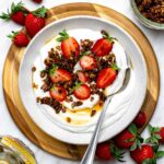 Blended cottage cheese served in a white bowl and topped with granola and strawberries.