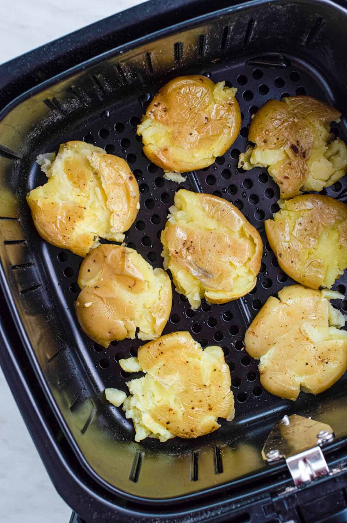 Uncooked smashed potatoes in air fryer basket.