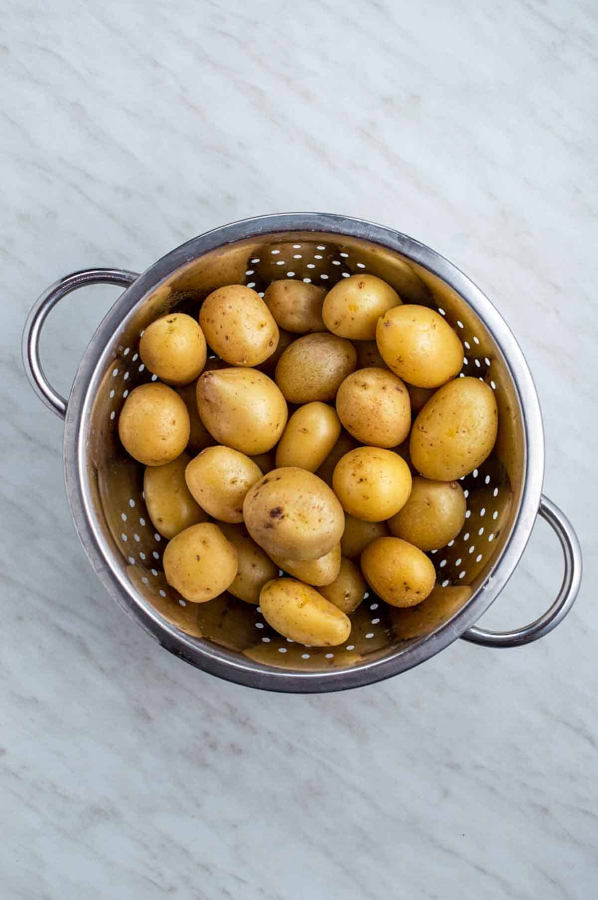 Cooked baby potatoes draining in a colander.