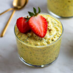 A glass cup filled with overnight oats and topped with sliced strawberries.