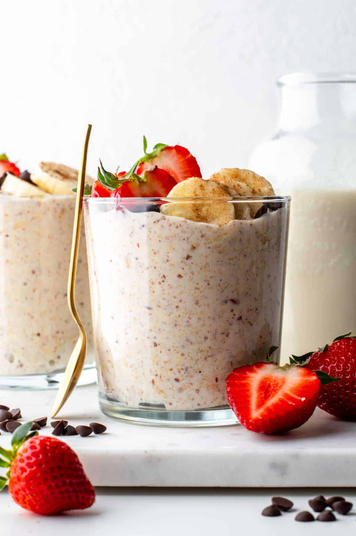 Flaxseed overnight oats in a glass cup topped with banana slices and halved strawberries.