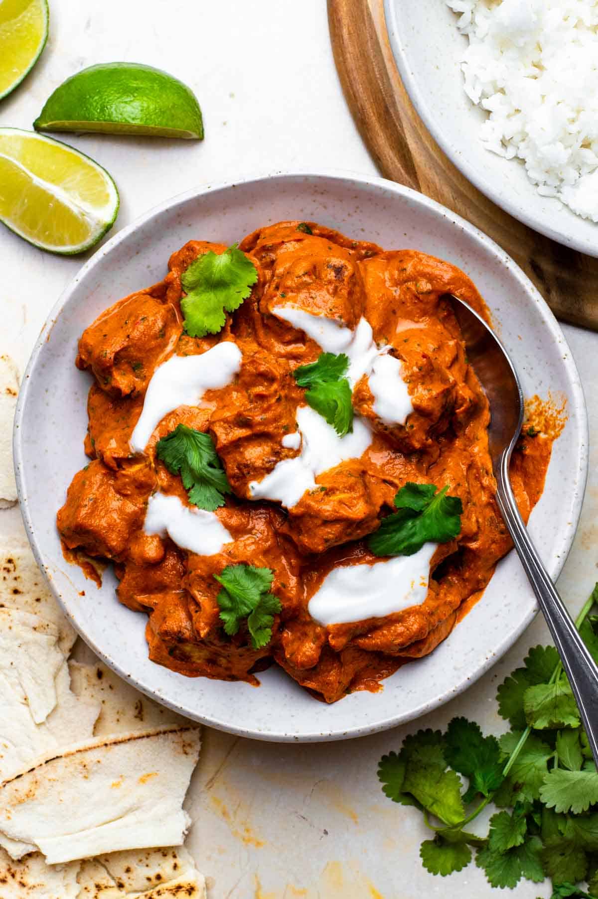 Curry without coconut milk served in a white bowl and topped with yogurt and cilantro.