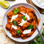 Curry without coconut milk served in a white bowl and topped with yogurt and cilantro.