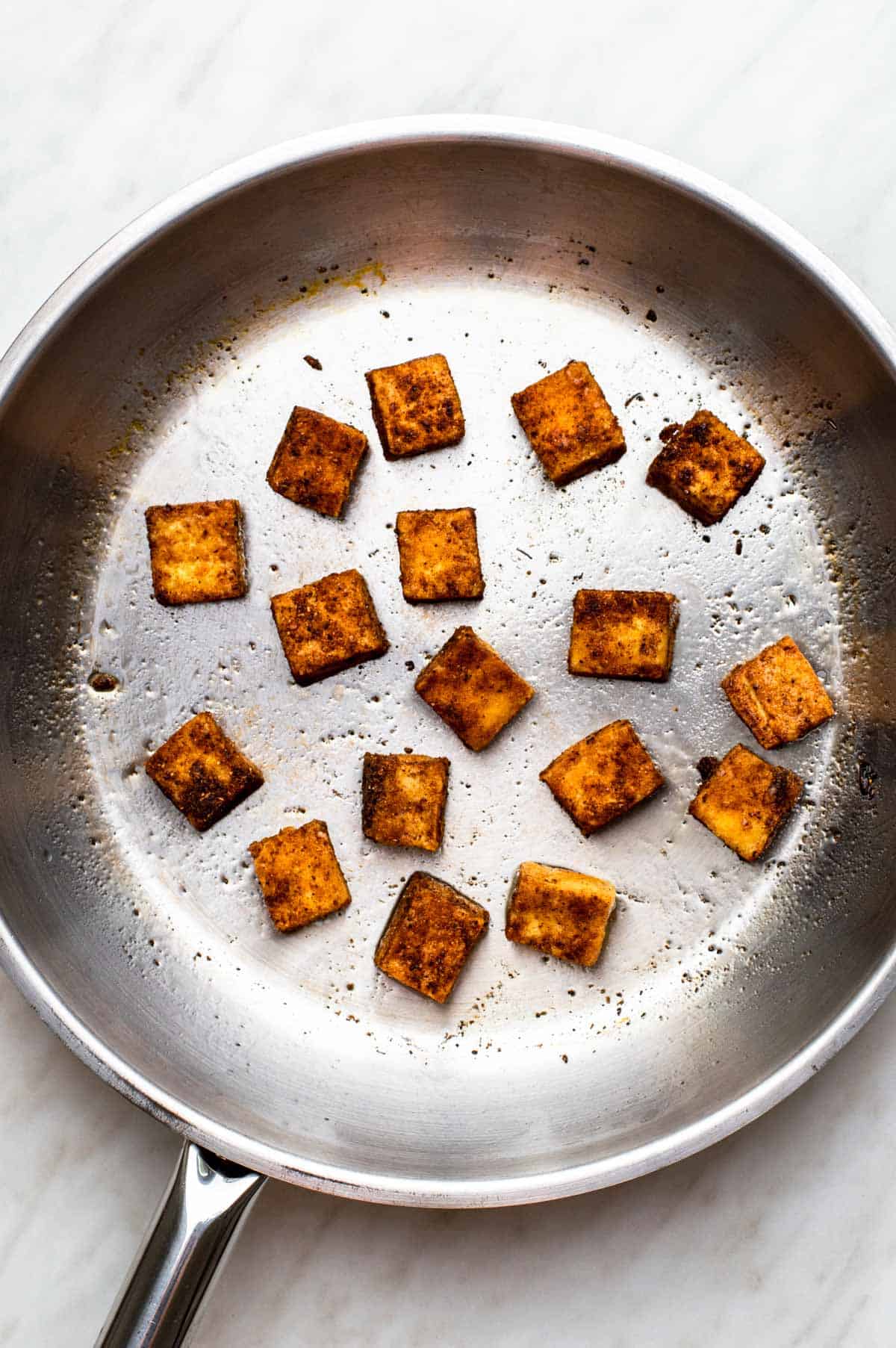 Frying tofu in a stainless-steel pan.