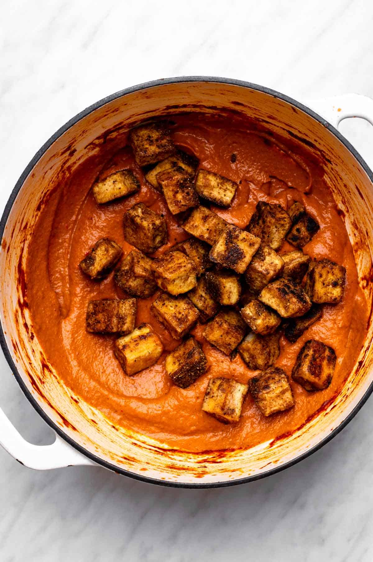 Adding fried tofu cubes to tomato gravy.