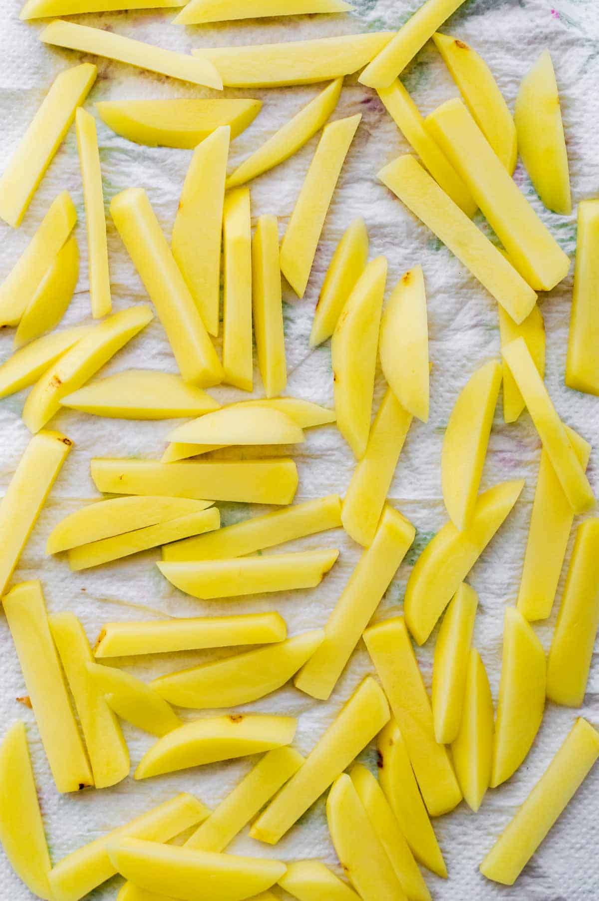 Raw sliced potatoes drying on a piece of paper towel.