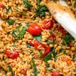 Baked tomato orzo in a white baking dish.
