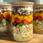Greek pasta salad layered in a tall glass jar.