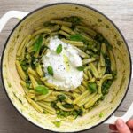 Pea pesto pasta in a white Dutch oven topped with burrata.