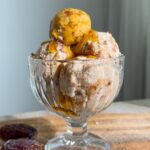 Salted caramel ice cream serve in a glass cup topped with caramel sauce.
