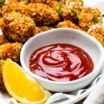 A small bowl filled with homemade ketchup next to vegan chicken nuggets.