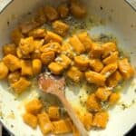 Pumpkin gnocchi in a white wine sauce cooked in a white Dutch oven.