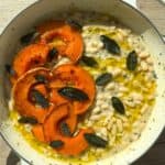 Fagioli All’Olio in a white dutch oven topped with roasted squash, fried sage leaves and olive oil.