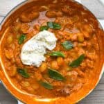 Gnocchi in a red pepper sauce topped with burrata and basil leaves.
