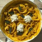 Pumpkin sage pasta in a white Dutch oven topped with burrata cheese.