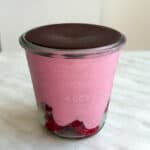 Raspberry blended oats in a glass jar topped with melted chocolate.