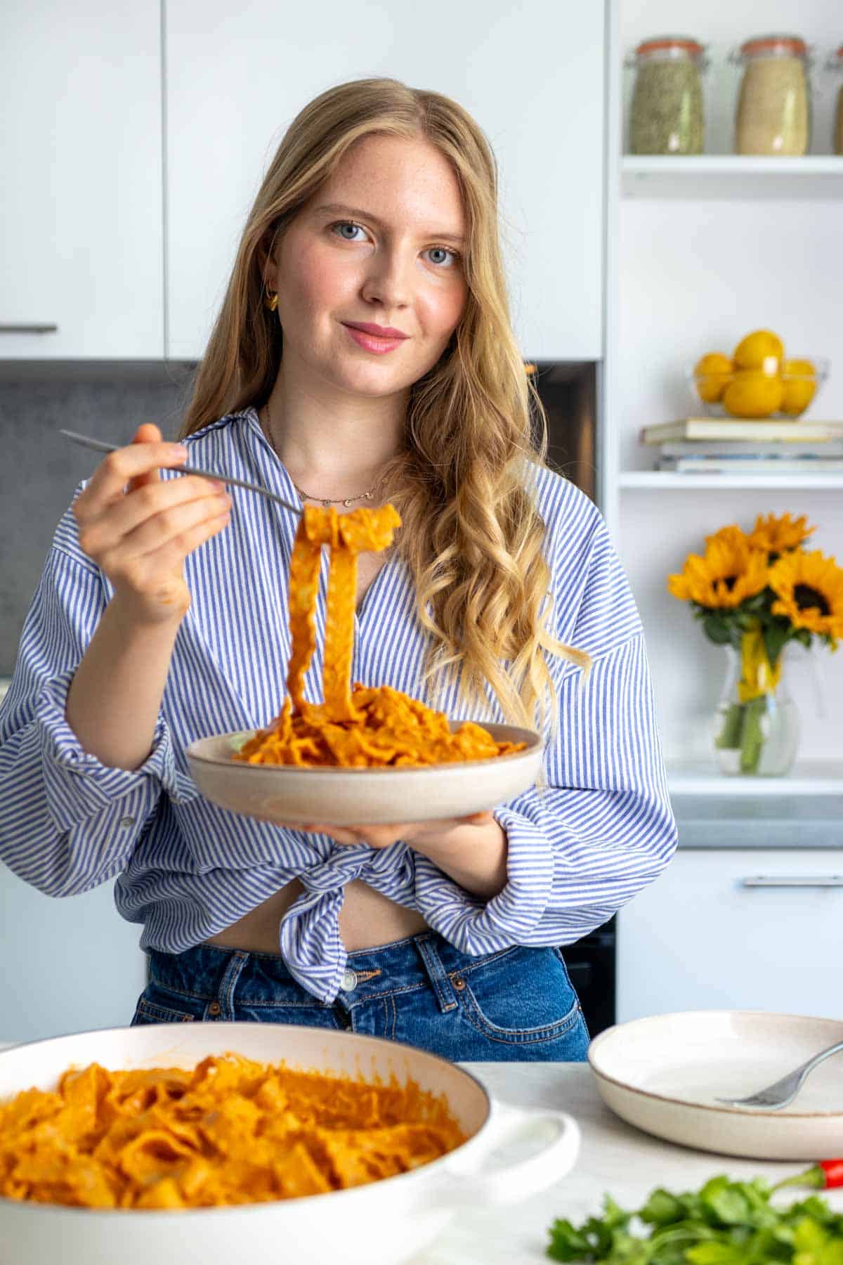 A photo of Petranka, found of Sunglow Kitchen, holding a plate of sun-dried tomato pasta.