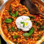 Tomato orzo cooked in a white Dutch oven topped with a burrata ball, fresh basil and a drizzle of olive oil.