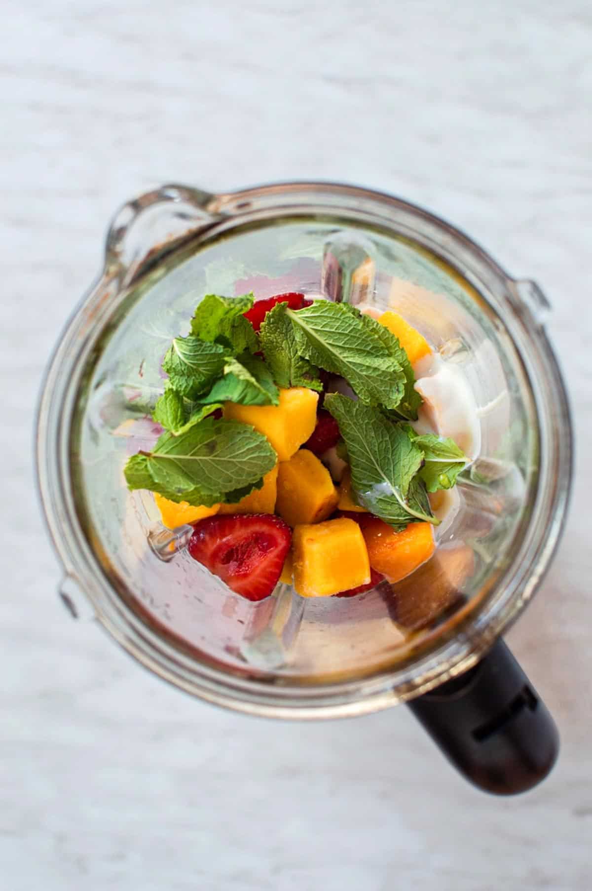 Ingredients to make an avocado smoothie with mango instead of banana added to a blender. 