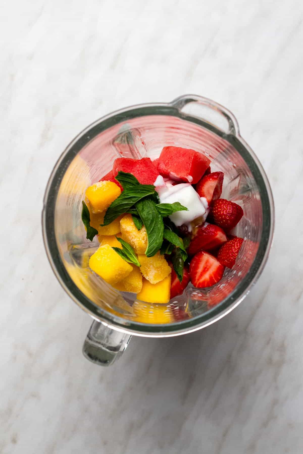 Ingredients for a watermelon and mango smoothie added to the blender.
