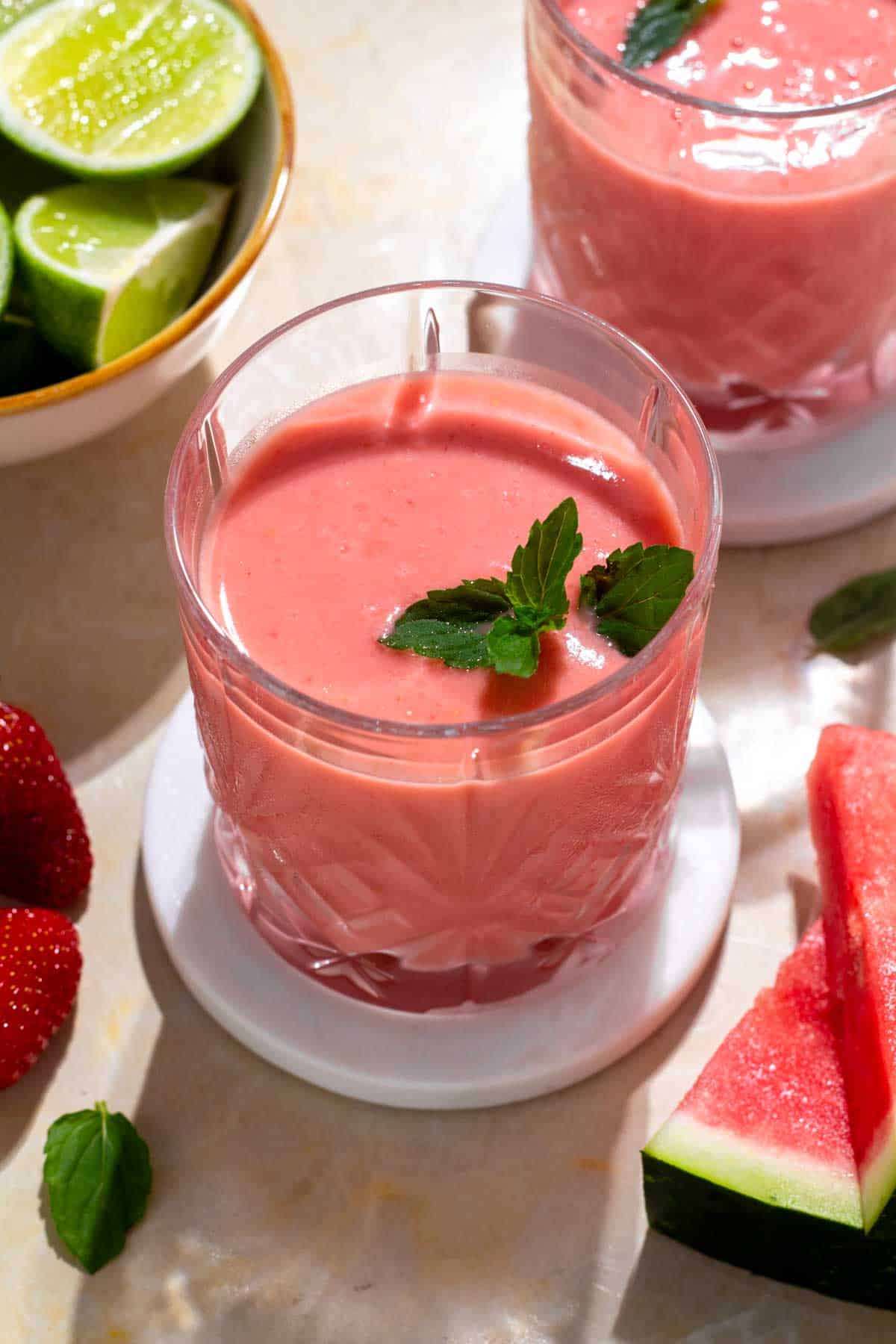 Glasses filled with a mango watermelon smoothie on a table.