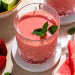 Watermelon mango smoothie in a glass on a white plate.