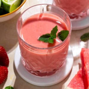 Watermelon mango smoothie in a glass on a white plate.
