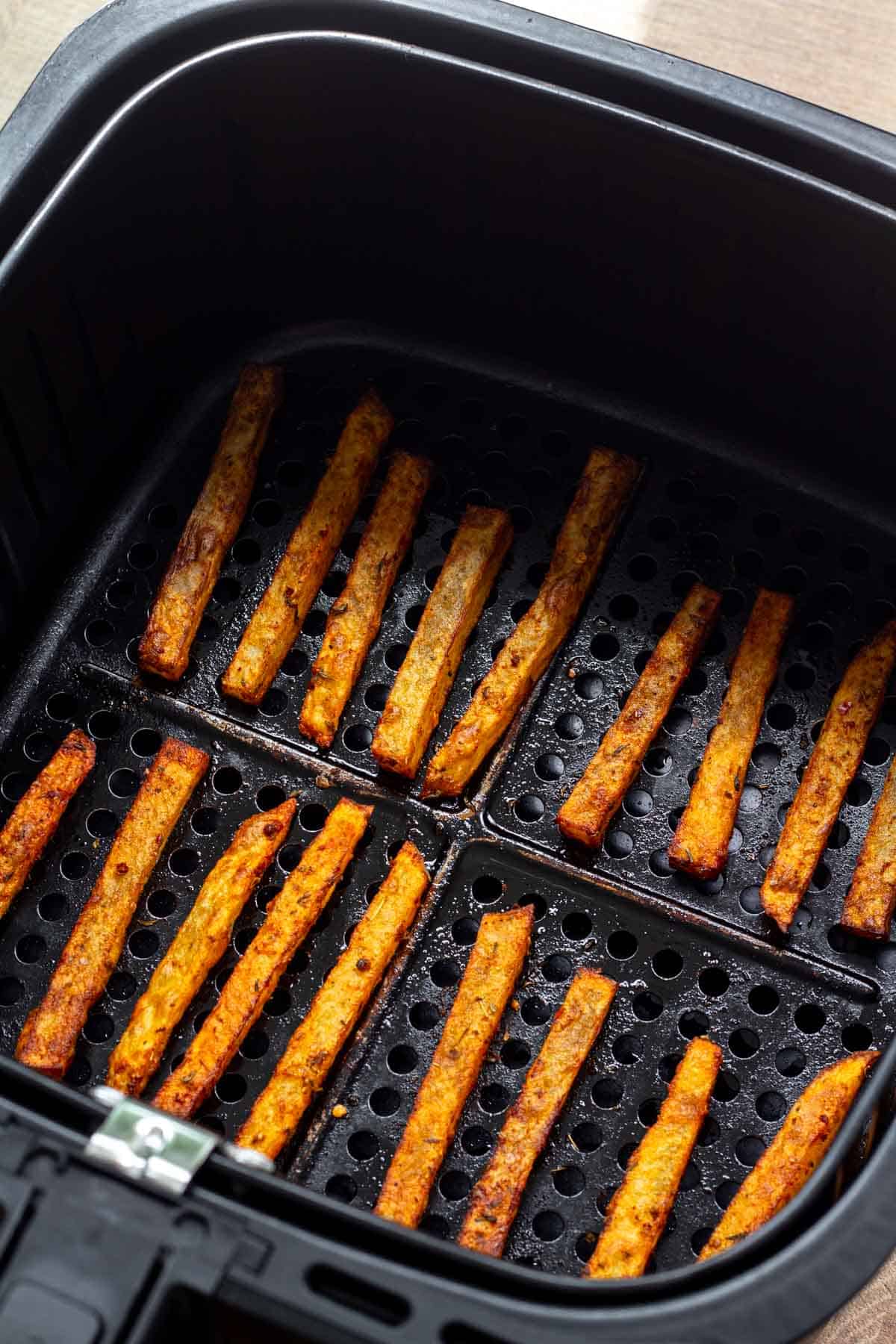 Air fried cajun fries resting in the air fryer basked.