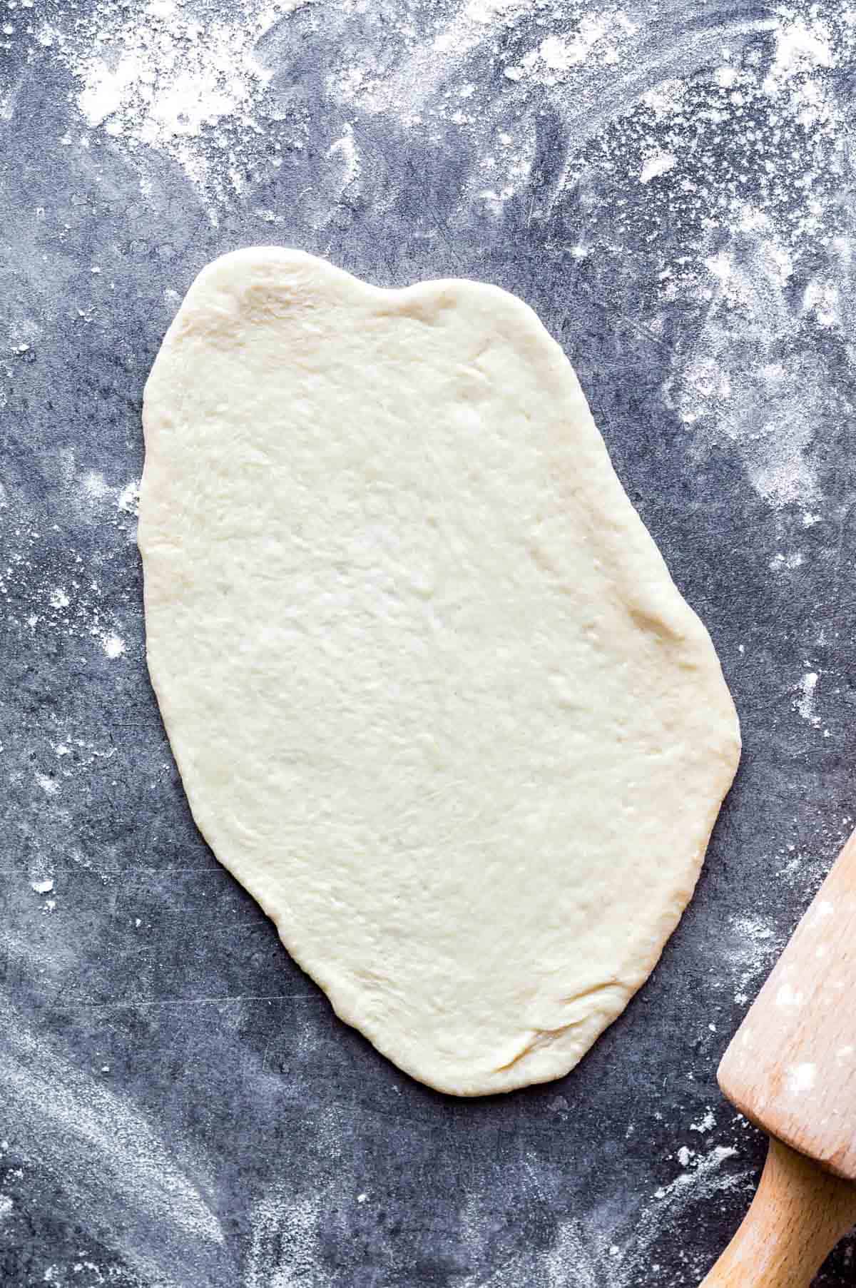 Rolled out dough on a kitchen countertop sprinkled with flour.