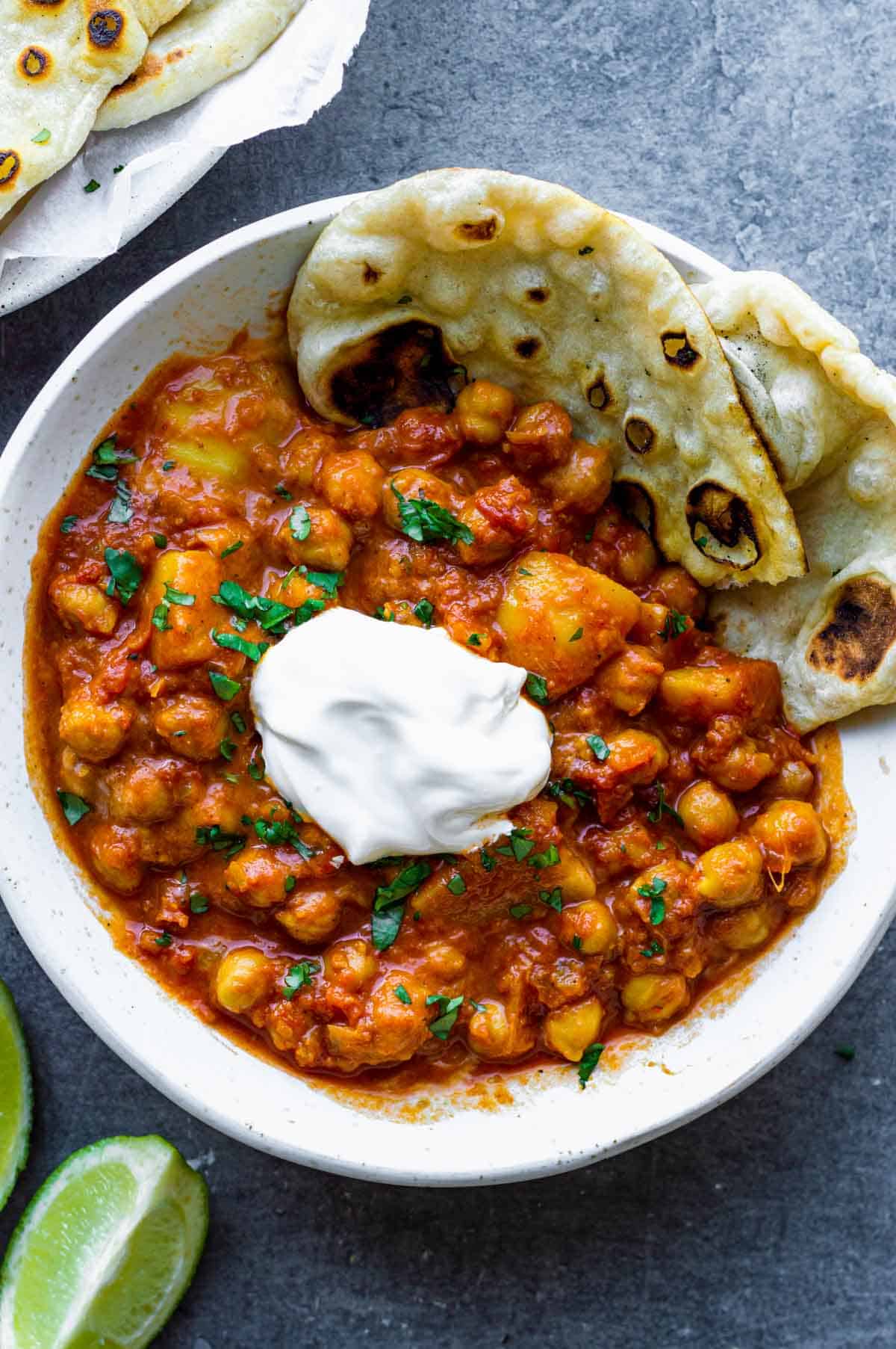 Homemade naan with a bowl of chickpea curry topped with sour cream.