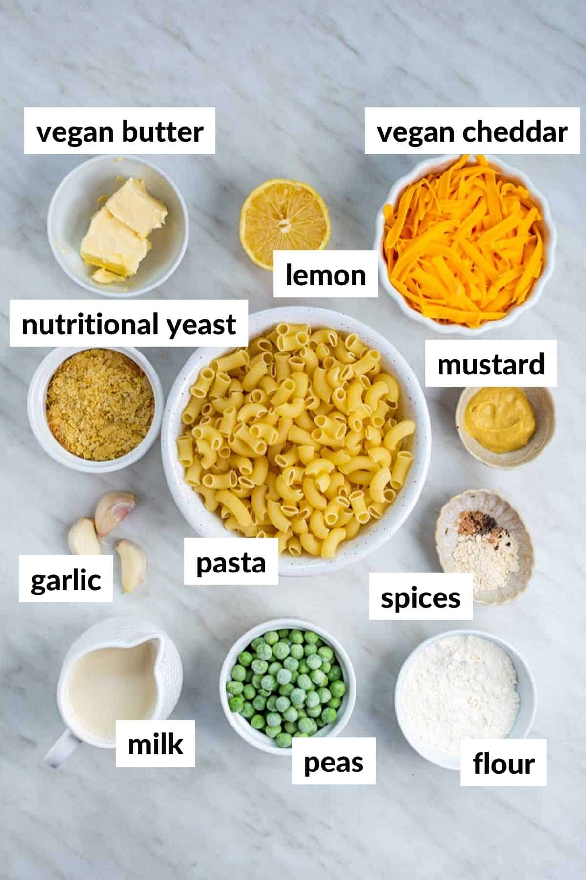 Ingredients for making vegan mac and cheese on a white countertop, with text overlay on each ingredient.